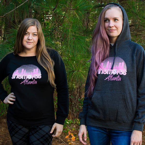 Two women wearing SheMoves Atlanta sweatshirts