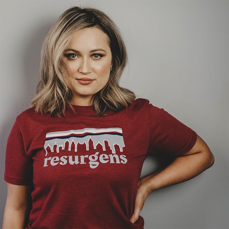 Burgundy tshirt branded for Resurgens on a smiling woman